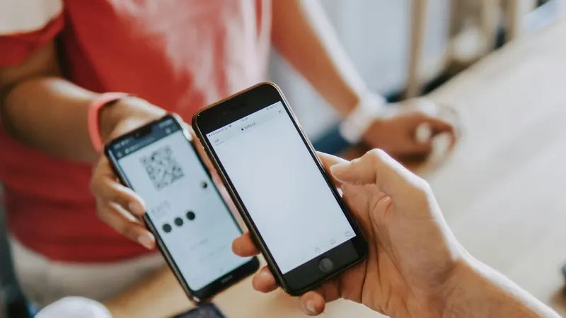 Two people using phones to scan a payment QR code