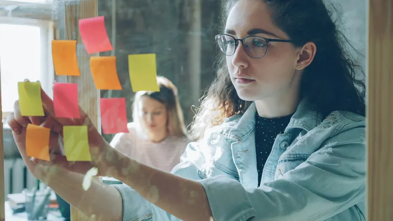 A product team arranging sticky notes on a glass wall
